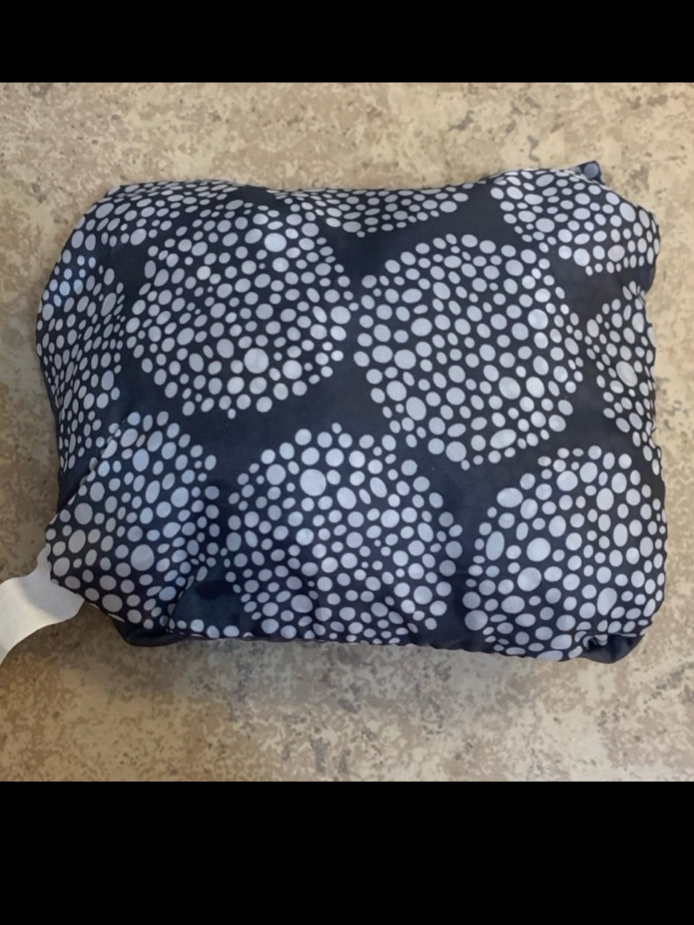 Folded IKEA Knalla portable travel backpack in grey with white polka-dot pattern